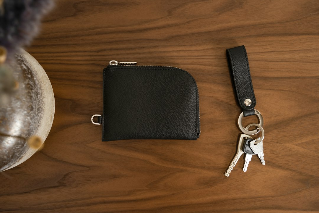 Black leather wallet and keys on a wooden table